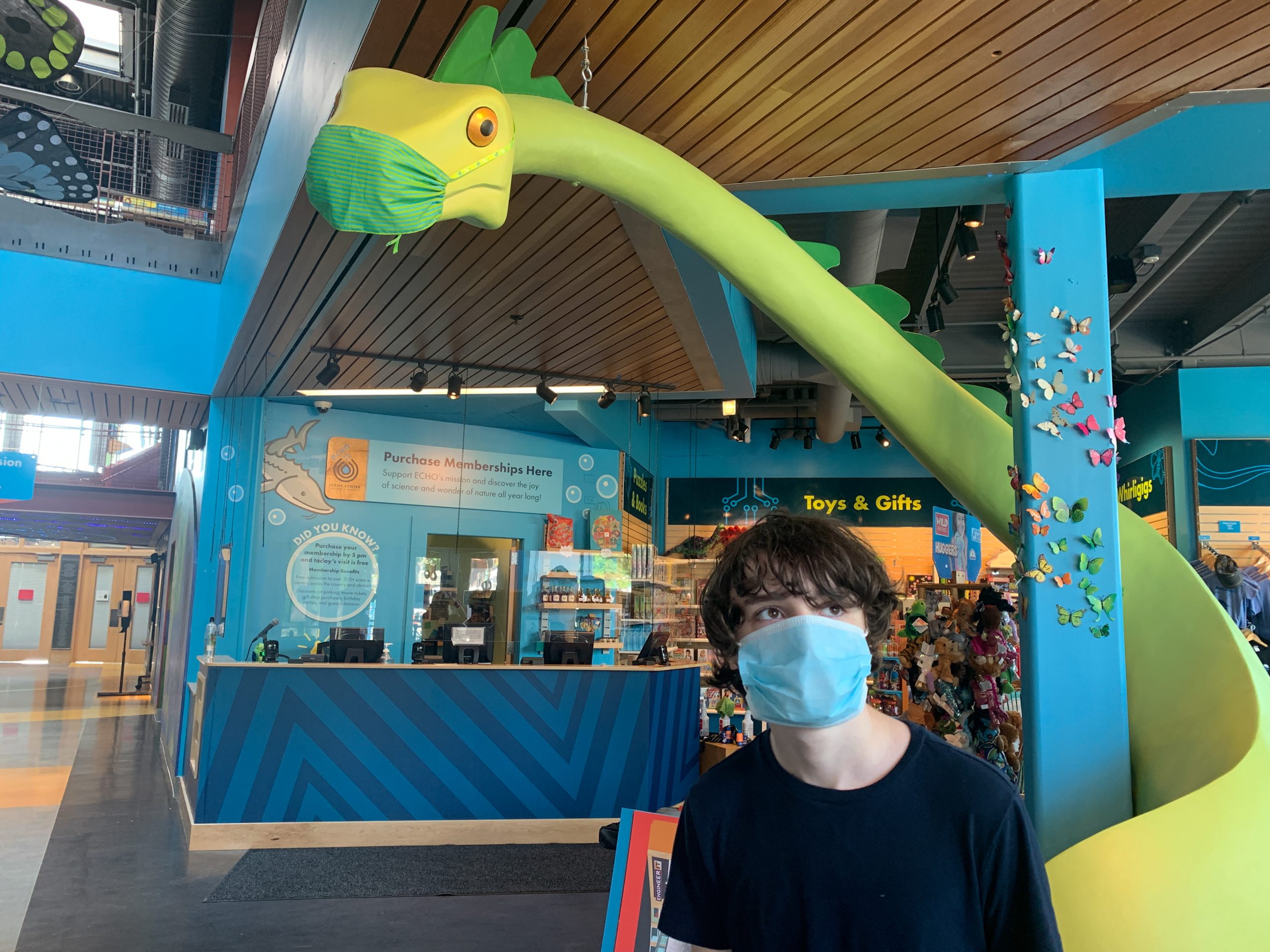 Child with mask on next to the Gift Shop's champ with a mask on