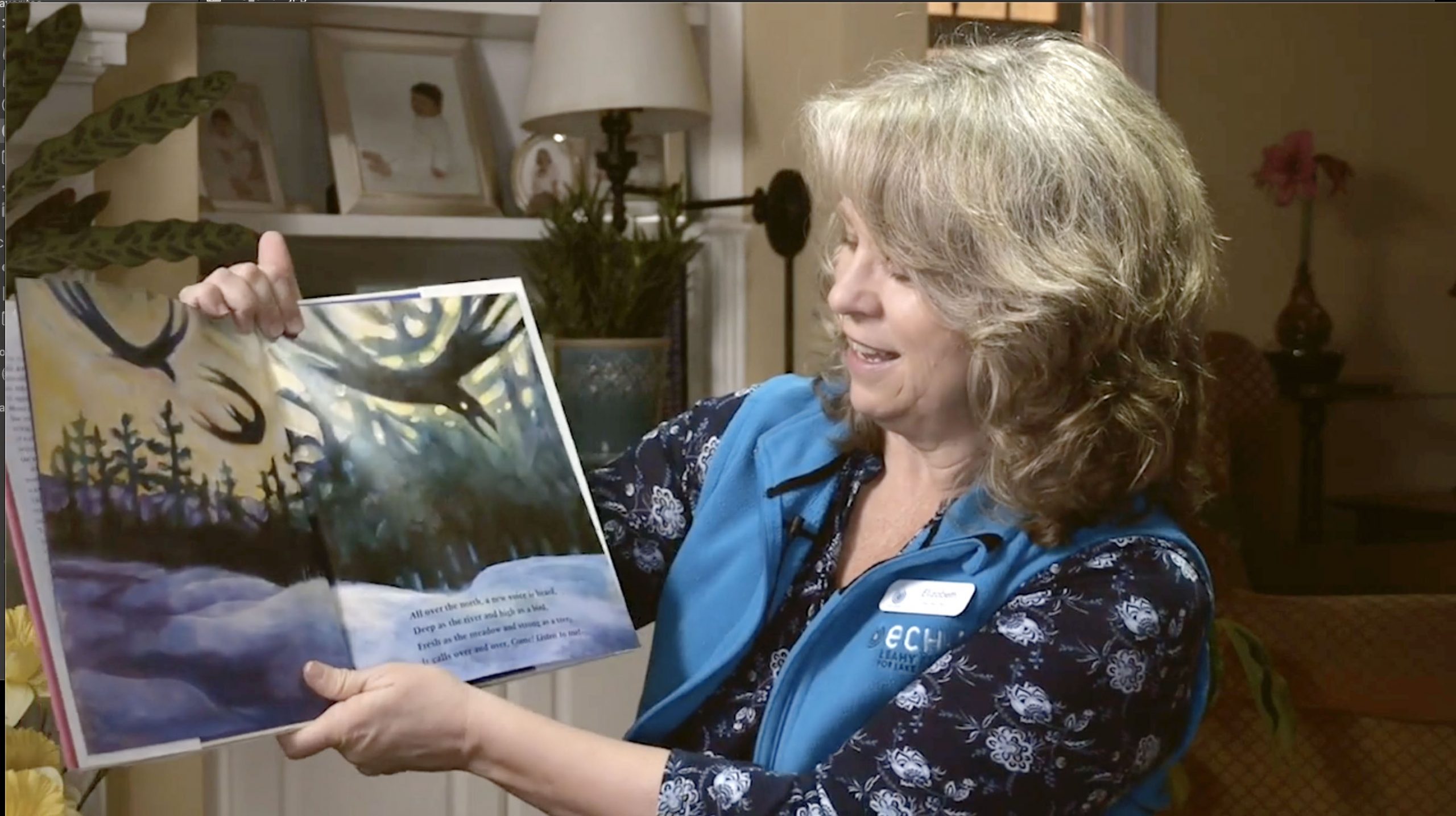 Elizabeth with blonde hair and blue ECHO Vest holds up the book she is reading about spring.