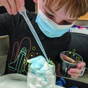 child with dropper putting colors on shaving cream