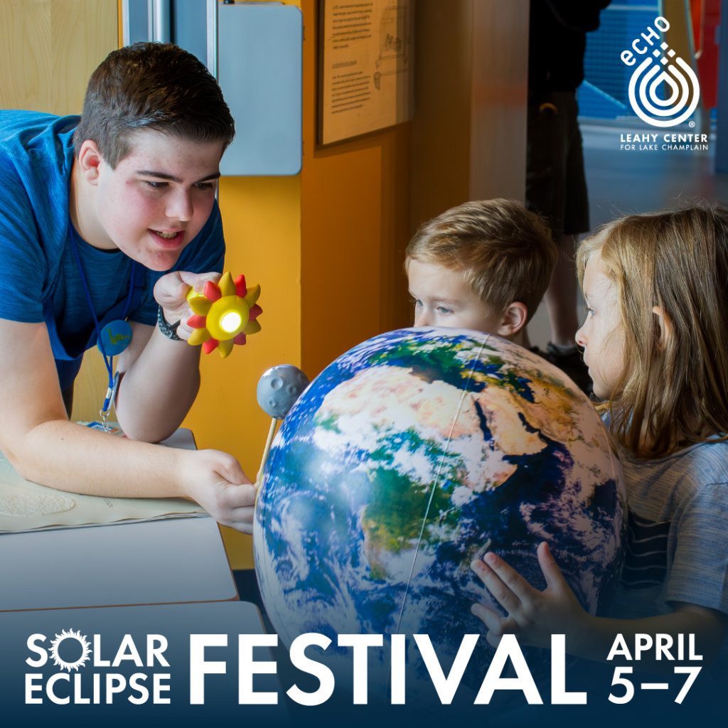 A photo of an ECHO intern using a flashlight to simulate an eclipse against an inflatable Earth held by two young guests. White text reads Solar Eclipse Festival April 5-7