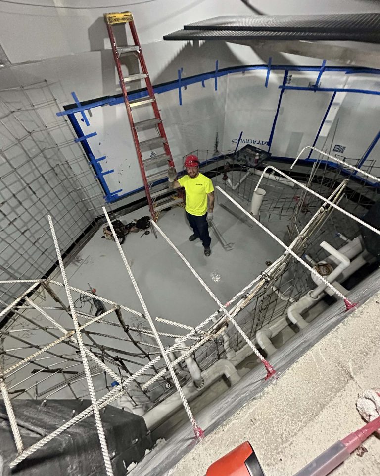 Man in yellow shirt waves while standing in the middle of the new Lake Tank.