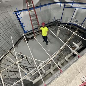 Man in yellow shirt waves while standing in the middle of the new Lake Tank.