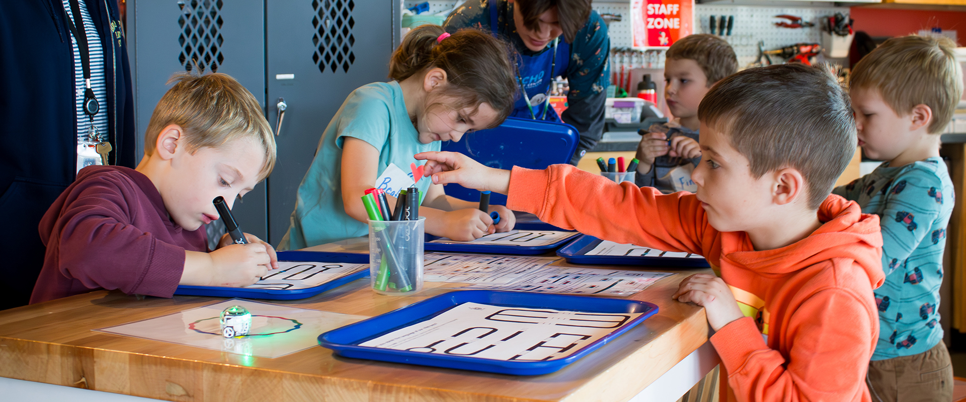 Image of several school-age children working on ECHO's ozobots engineering challenge