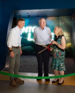 Ted Lawson smiles at Senator Patrick Leahy and Marcelle Leahy with large scissors