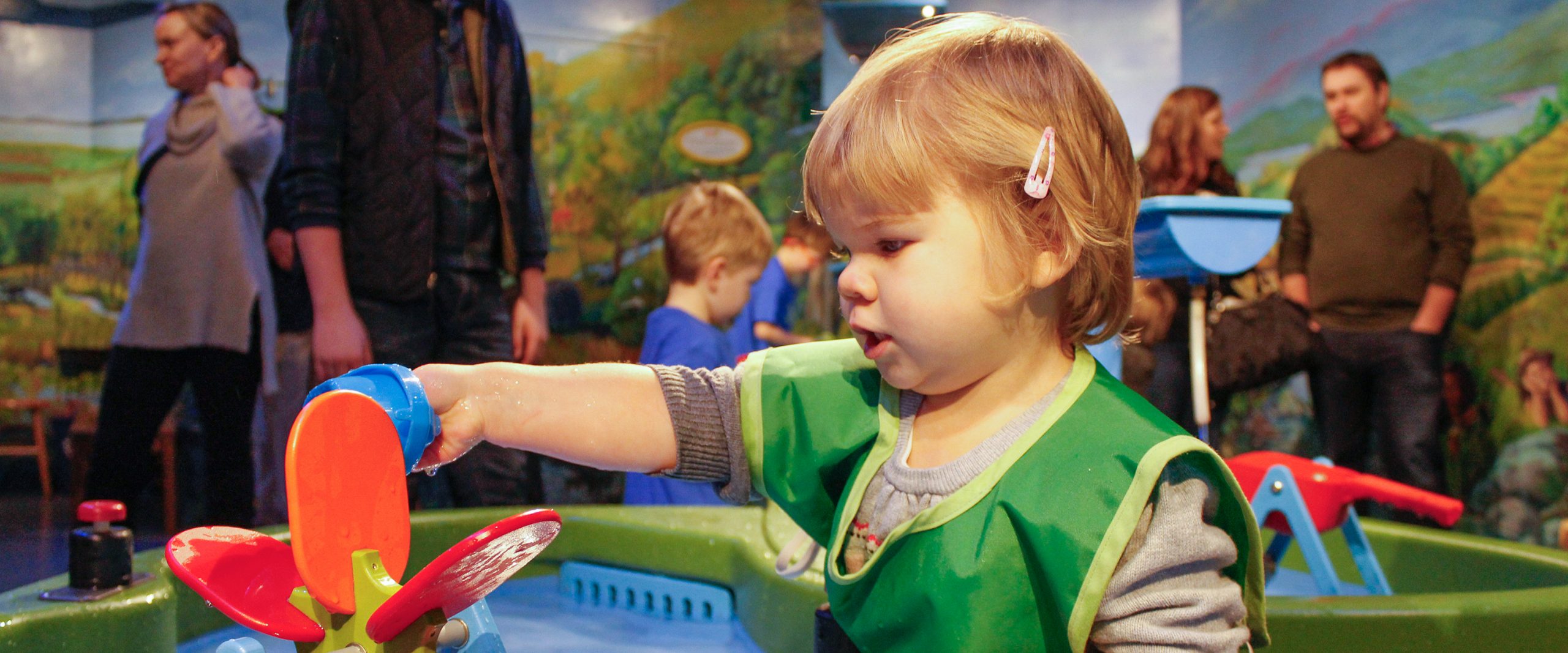 Image of a small child playing at the water play table in Champ Lane