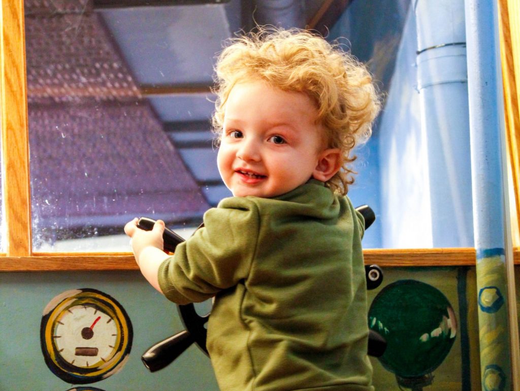 A small child pretending to pilot a boat in Champ Lane